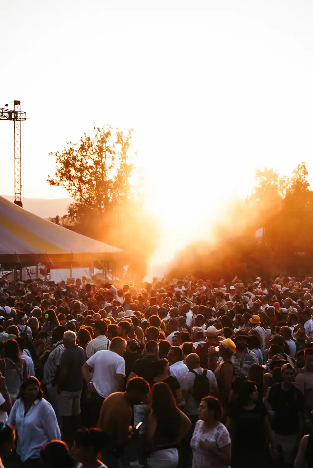 Grande foule à un festival en plein air au coucher du soleil, avec brume orange.